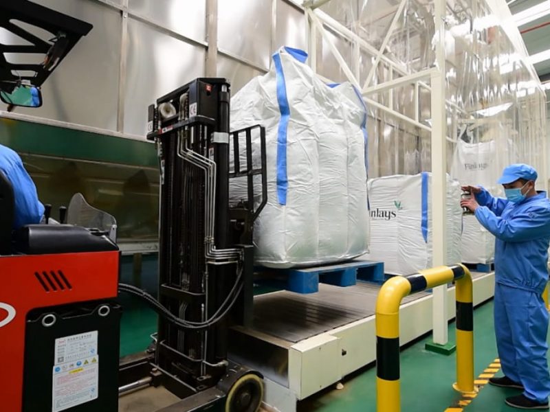 Finlays' employee working with large bags of tea in Guizhou factory
