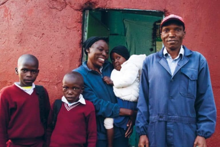 Kenyan family standing by a house