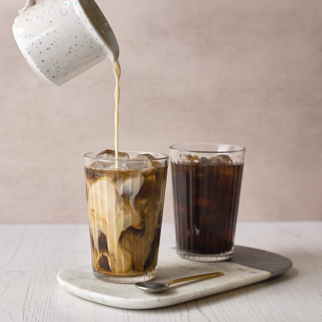 Milk poured into two glasses of cold brew coffee